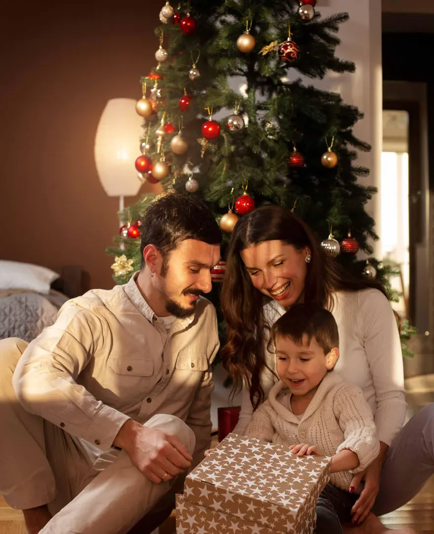 Familia abriendo un regalo junto al árbol de Navidad